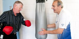 Two elderly men boxing with gloves and a punching bag