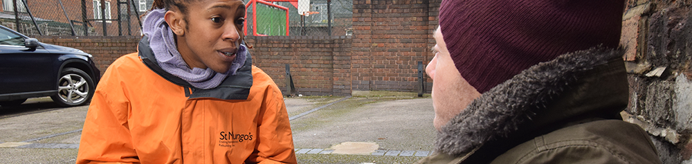 Woman in uniform talking to a homeless man