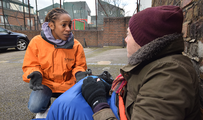 Woman in uniform talking to a homeless man