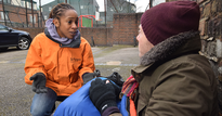 Woman in uniform talking to a homeless man