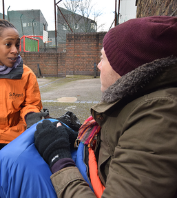 Woman in uniform talking to a homeless man
