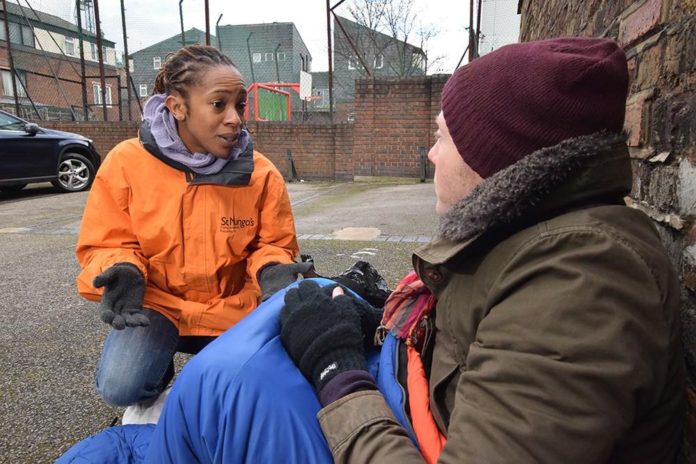 Woman in uniform talking to a homeless man