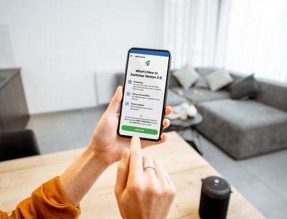 Hands holding a phone showing the Switchee app interface