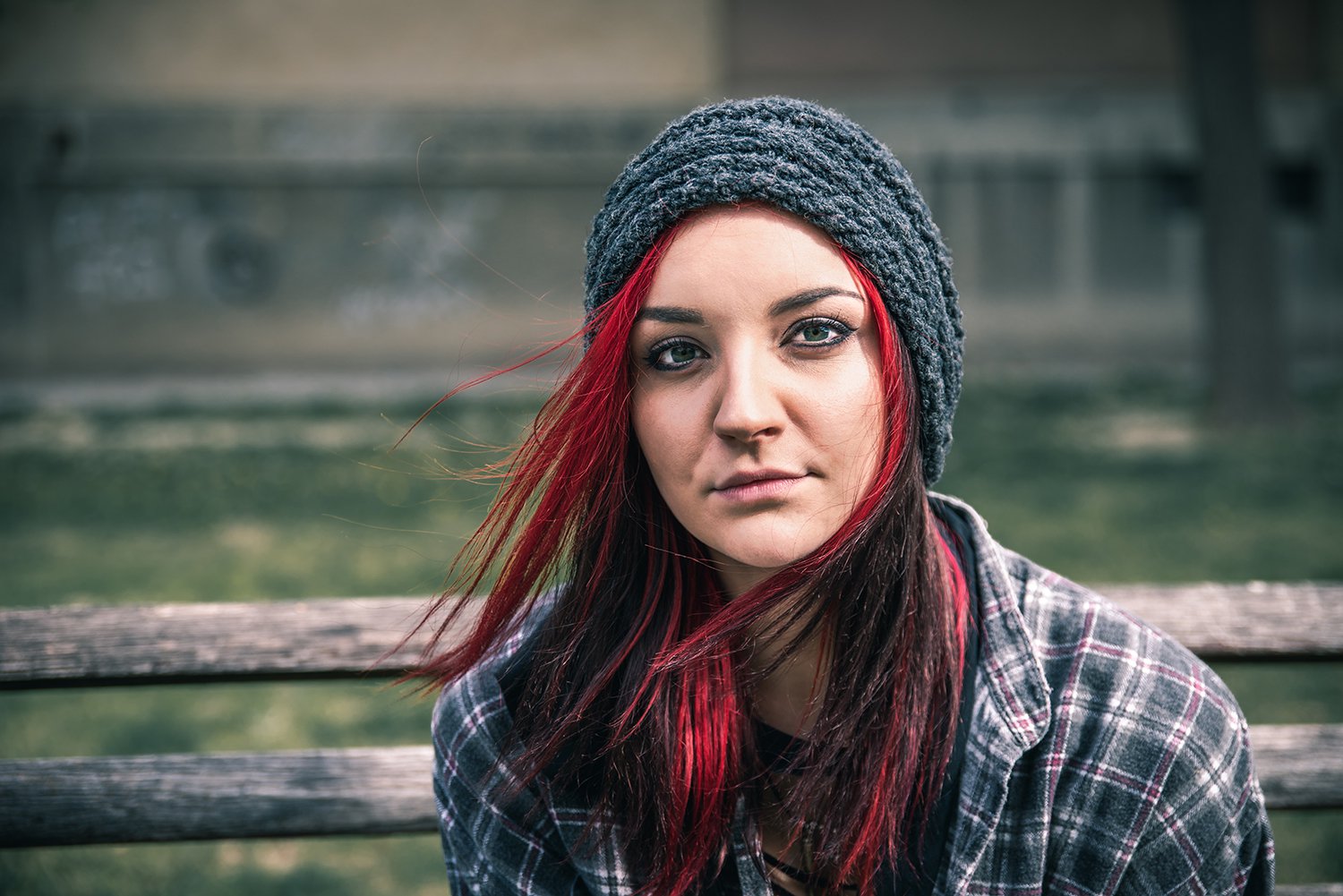 Woman with red hair and beanie sat on a bench