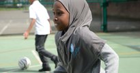Young girl wearing a grey hijab on a football pitch