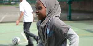 Young girl wearing a grey hijab on a football pitch