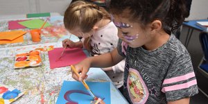 Two young girls painting in a class room