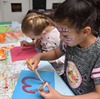 Two young girls painting in a class room