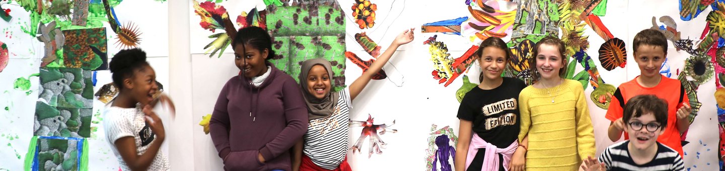 Group of young children smiling against a wall of colourful art