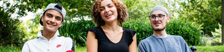 Two children sitting on a bench with an adult, smiling at the camera