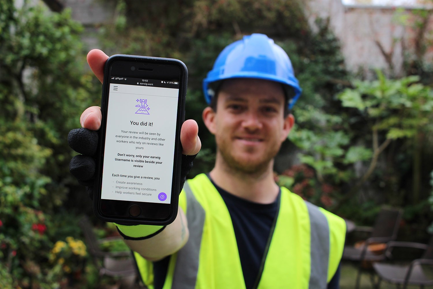 Worker from Worker Feedback Club holding phone