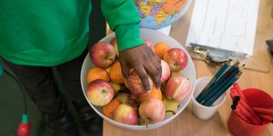 Child's hand reaching into a bowl of apples