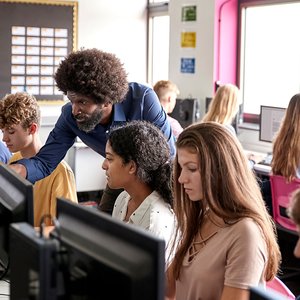 Teacher helping students develop digital skills in a classroom computer lab