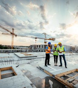 Construction workers reviewing plans at a large residential housing development site with cranes and new buildings under construction