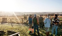 Community group meeting outdoors to discuss a climate and environmental project in a rural landscape