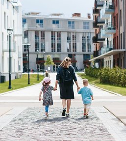 Parent walking with two children through a modern residential housing neighbourhood.