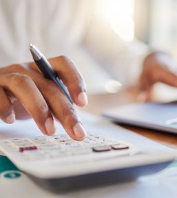 Stock image of someone in a shirt using a calculator and a laptop