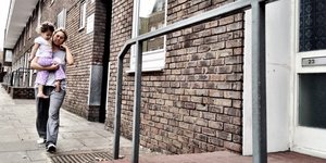 Woman carrying a child into a house