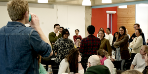 A group of people standing up in a space for a team building exercise