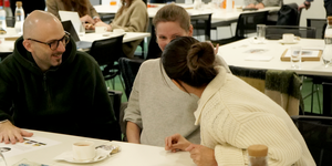 Three people sat around a table smiling and having a conversation